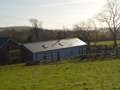 A rural property with a barn and wooden fencing on a grassy field at Cwrt y Wennol in Salem near Clydach
