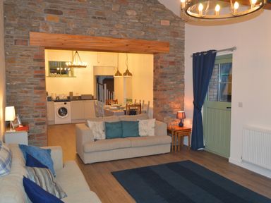 A living room with sofas a rug and a side table with a lamp opening to a kitchen and dining area at Cwrt y Wennol Salem near Clydach