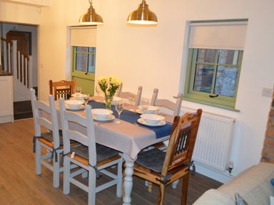 A dining room with a set table and chairs under pendant lights at Cwrt y Wennol in Salem near Clydach