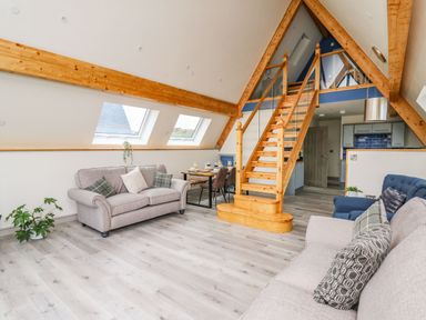 A living room with two sofas a dining table and chairs wooden staircase and exposed beams at Hill Radnor - The Sheepfold in Llanyre near Llandrindod Wells