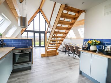 A kitchen and dining area with wooden stairs and large windows at Hill Radnor - The Sheepfold in Llanyre near Llandrindod Wells