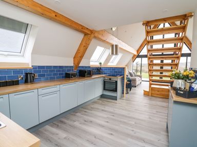 A kitchen with blue cabinets and wooden countertops blue tiled backsplash and wooden beams at Hill Radnor - The Sheepfold Llanyre near Llandrindod Wells