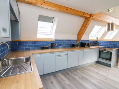 A kitchen with wooden countertops blue tiled backsplash and light blue cabinets at Hill Radnor - The Sheepfold in Llanyre near Llandrindod Wells