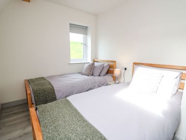 A bedroom with two single beds with wooden frames and a window at Hill Radnor - The Sheepfold in Llanyre near Llandrindod Wells