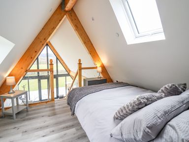 A bedroom with a double bed pillows two bedside tables with lamps and a skylight window at Hill Radnor - The Sheepfold in Llanyre near Llandrindod Wells