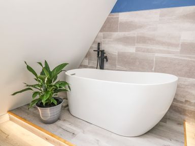 A bathroom with a freestanding bathtub and a potted plant on a wooden floor at Hill Radnor - The Sheepfold in Llanyre near Llandrindod Wells