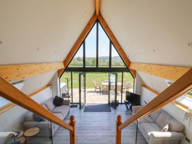 A living room with sofas a television and glass doors opening to a patio at Hill Radnor - The Sheepfold in Llanyre near Llandrindod Wells