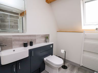 A bathroom with a sink, toilet, mirror, and window at Brecknock Cheviot - The Sheepfold in Llanyre near Llandrindod Wells