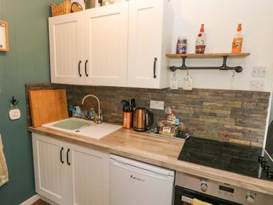 A kitchen countertop with a sink kettle stove and cabinet at Doirewood Penlan Holiday Park near Cenarth