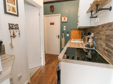 A kitchen with a stove sink countertop and key hooks on the wall at Doirewood Penlan Holiday Park near Cenarth