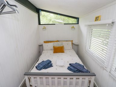 A bedroom with a bed with pillows and folded towels near a window with blinds at Doirewood Penlan Holiday Park near Cenarth