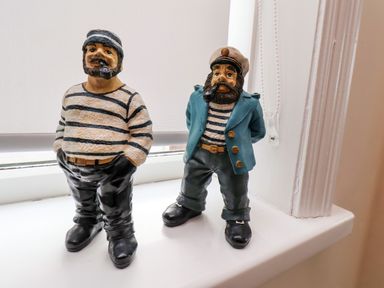Two sailor figurines wearing striped shirts and black shoes on a windowsill at Over Esk in Whitby