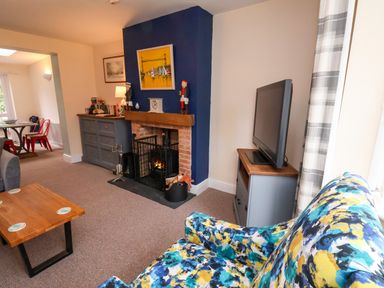 A living room with a fireplace television and a colorful sofa at Over Esk in Whitby