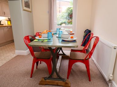 A dining area with a table set for four with red chairs and a door leading outside at Over Esk in Whitby