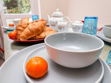 A table set with croissants on a plate tangerines white bowls and blue glasses at Over Esk in Whitby