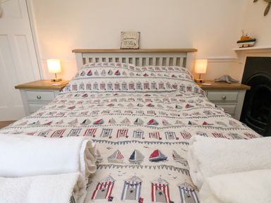 A bedroom with a bed covered in nautical-themed bedding and two bedside tables with lamps at Over Esk in Whitby