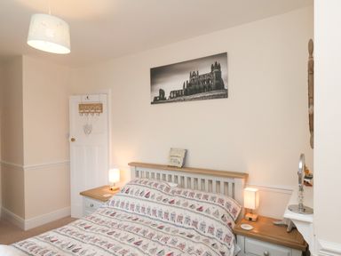 A bedroom with a bed surrounded by two bedside tables and lamps and a door in the corner at Over Esk in Whitby