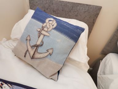 A bed with white sheets and a cushion with an anchor design at Over Esk in Whitby