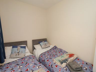A bedroom with two single beds with anchor themed pillows and blankets at Over Esk in Whitby