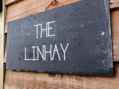 A black rectangular sign with the words The Linhay mounted on a wooden wall at The Linhay in Cadeleigh near Tiverton