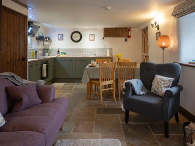 An open plan kitchen and dining area with wooden chairs and a grey armchair at Wavering in Compton Bishop near Axbridge