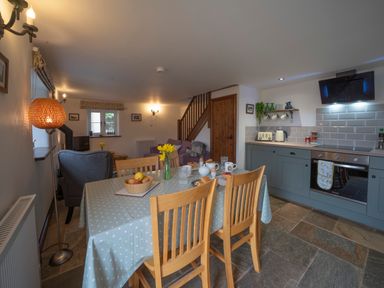 A kitchen and dining area with a table set for breakfast and a sitting area with armchairs at Wavering in Compton Bishop near Axbridge