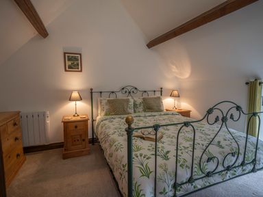 A bedroom with a metal bed frame floral bedding wooden bedside tables with lamps and wooden dresser at Wavering Compton Bishop near Axbridge