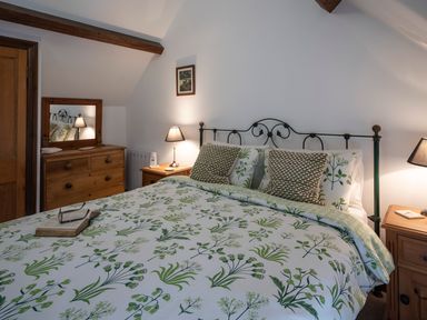 A bedroom with a bed floral bedding wooden dresser and bedside tables with lamps at Wavering Compton Bishop near Axbridge
