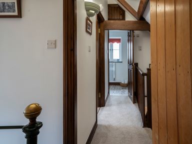 A hallway with carpet leading to a bathroom with tiled floor and window at Wavering Compton Bishop near Axbridge
