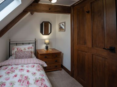 A bedroom with a single bed floral bedding wooden chest of drawers and wooden door at Wavering Compton Bishop near Axbridge