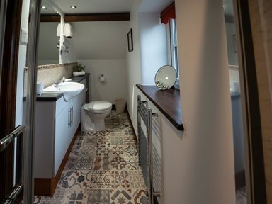 A bathroom with a toilet sink cabinet and patterned floor tiles at Wavering in Compton Bishop near Axbridge