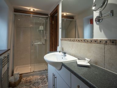 A bathroom with a shower enclosure a white sink countertop and a basket with towels at Wavering in Compton Bishop near Axbridge