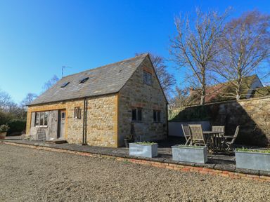 A stone cottage with wooden door and windows and outdoor seating area at Granary Cottage Blackwell near Ilmington