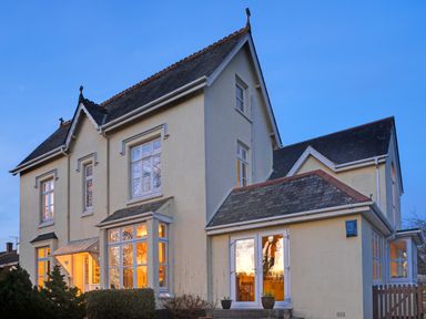 A two story cream colored house with multiple windows and a slate roof at Victoria Lodge in Kingsbridge