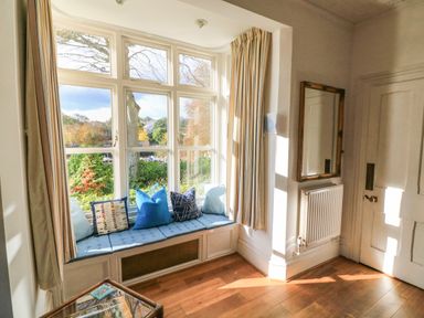 A window seat with blue cushions and pillows next to a radiator and a mirror at Victoria Lodge in Kingsbridge