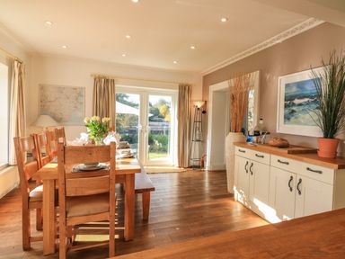 A dining room with wooden table and chairs and a sideboard with plants at Victoria Lodge in Kingsbridge