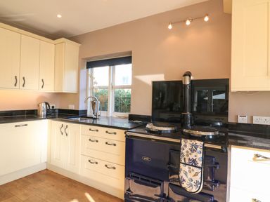 A kitchen with cream cabinets black countertop and a blue aga stove at Victoria Lodge in Kingsbridge