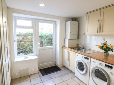 A utility room with a washing machine dryer sink and cabinets at Victoria Lodge in Kingsbridge