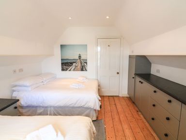 A bedroom with two beds a wooden floor built in cupboards and a door at Victoria Lodge in Kingsbridge