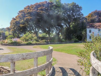 A garden with trees flowers and a wooden fence near a white building at Victoria Lodge in Kingsbridge