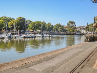 A view of boats docked along a river with trees and buildings in the background at Victoria Lodge in Kingsbridge