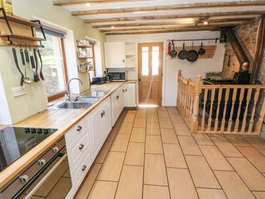 A kitchen with wooden countertops white cabinets a double sink stove microwave and hanging pans at Nant Moel Isaf Farm Rhydyfro near Pontardawe