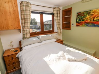 A bedroom with a double bed two bedside tables and a window with plaid curtains at Nant Moel Isaf Farm in Rhydyfro near Pontardawe