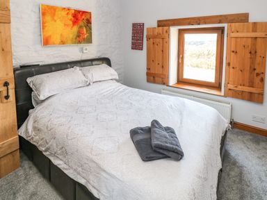 A bedroom with a bed and folded towels on it next to a window with wooden shutters at Nant Moel Isaf Farm in Rhydyfro near Pontardawe