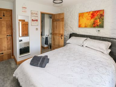 A bedroom with a bed white bedding with patterned pillows a wall mirror and a wooden door at Nant Moel Isaf Farm in Rhydyfro near Pontardawe