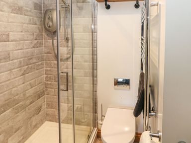 A bathroom with a glass shower enclosure and a wall-mounted toilet at Nant Moel Isaf Farm in Rhydyfro near Pontardawe
