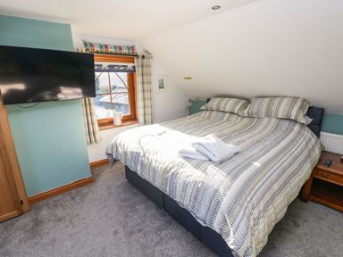 A bedroom with a bed and television on the wall at Nant Moel Isaf Farm in Rhydyfro near Pontardawe
