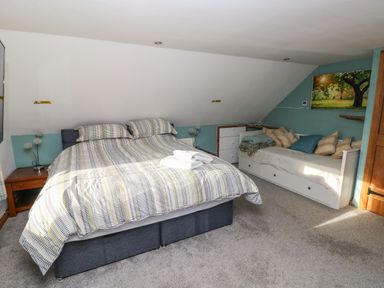 A bedroom with a double bed and a daybed with cushions and storage drawers at Nant Moel Isaf Farm in Rhydyfro near Pontardawe