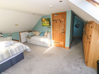 A bedroom with a bed a daybed a wooden door and built in wooden wardrobes at Nant Moel Isaf Farm in Rhydyfro near Pontardawe