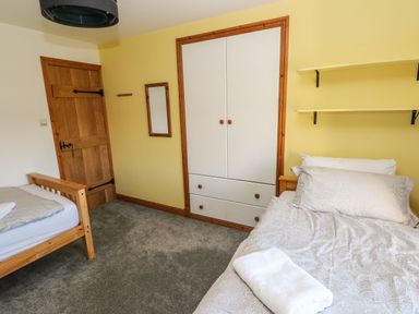 A bedroom with two single beds a wooden door a built in wardrobe and shelves at Nant Moel Isaf Farm Rhydyfro near Pontardawe